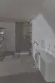 Modernes Bad mit Dusche und freistehender Badewanne. Handtücher und Pflegeprodukte auf einem Regal. Ideal Standard Thermostat für die Dusche sichtbar an der Wand angebracht.